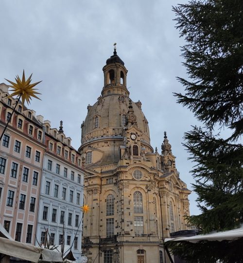 Die Frauenkirche in Dresden. Davor befindet sich ein kleiner Weihnachtsmarkt auf dem Dresdner Neumarkt.